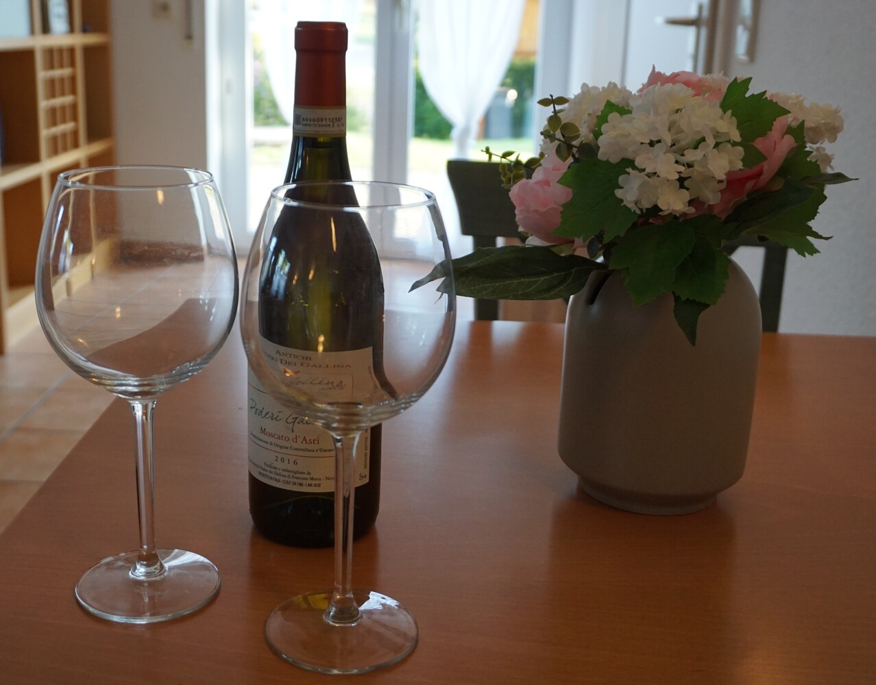 Wein mit Gläsern und Blumenstrauß